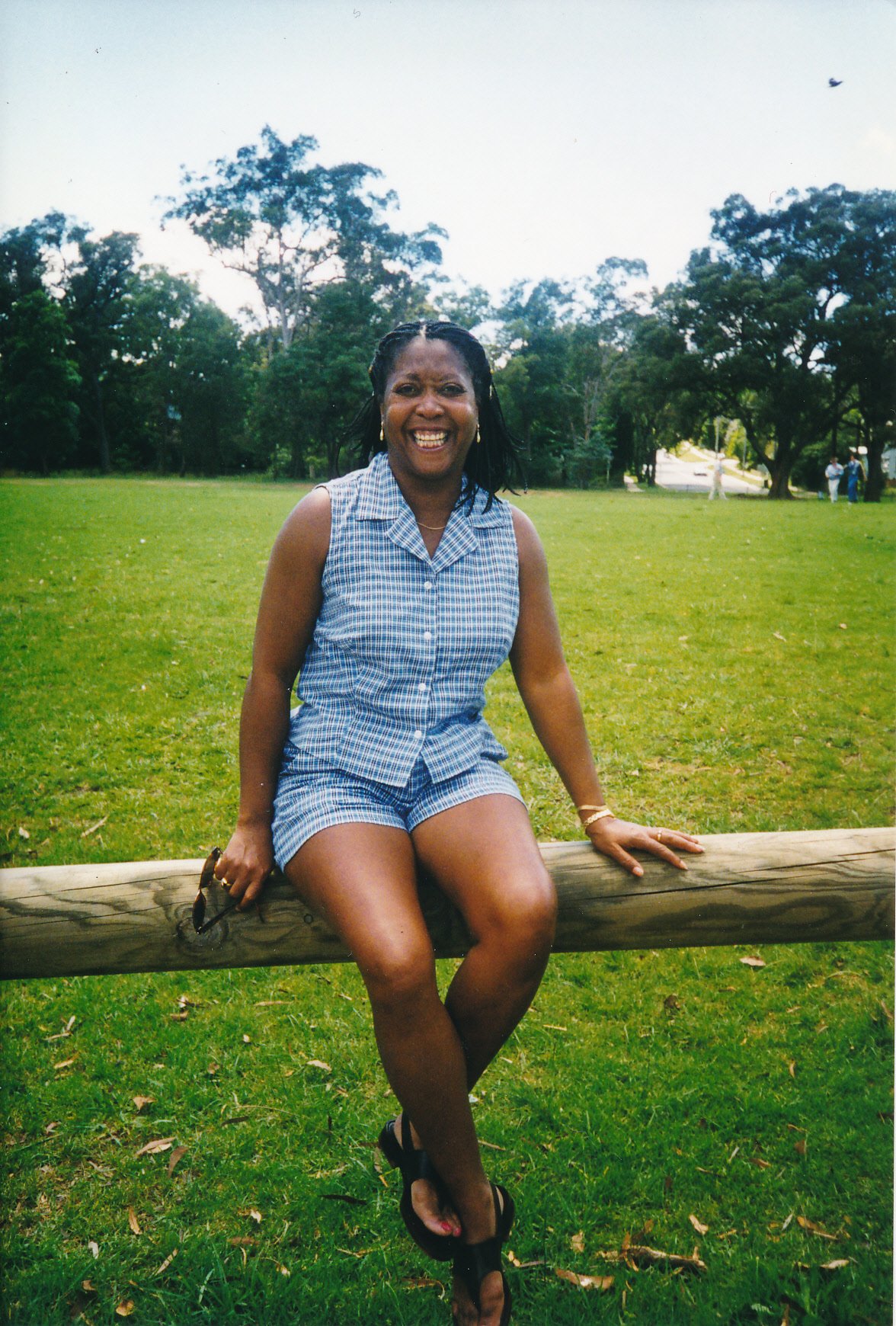 Arlinda sitting on a wooden post fence